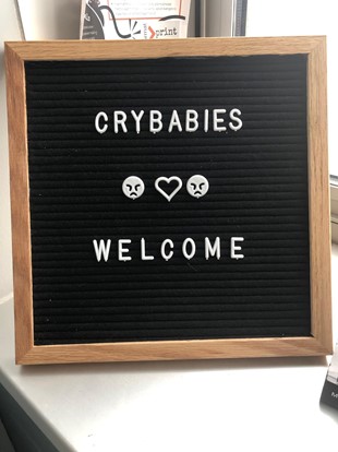 A felt board sign in Rachel and Elise’s writing center office that says “CRYBABIES WELCOME” with a heart between two frowny faces in the middle.